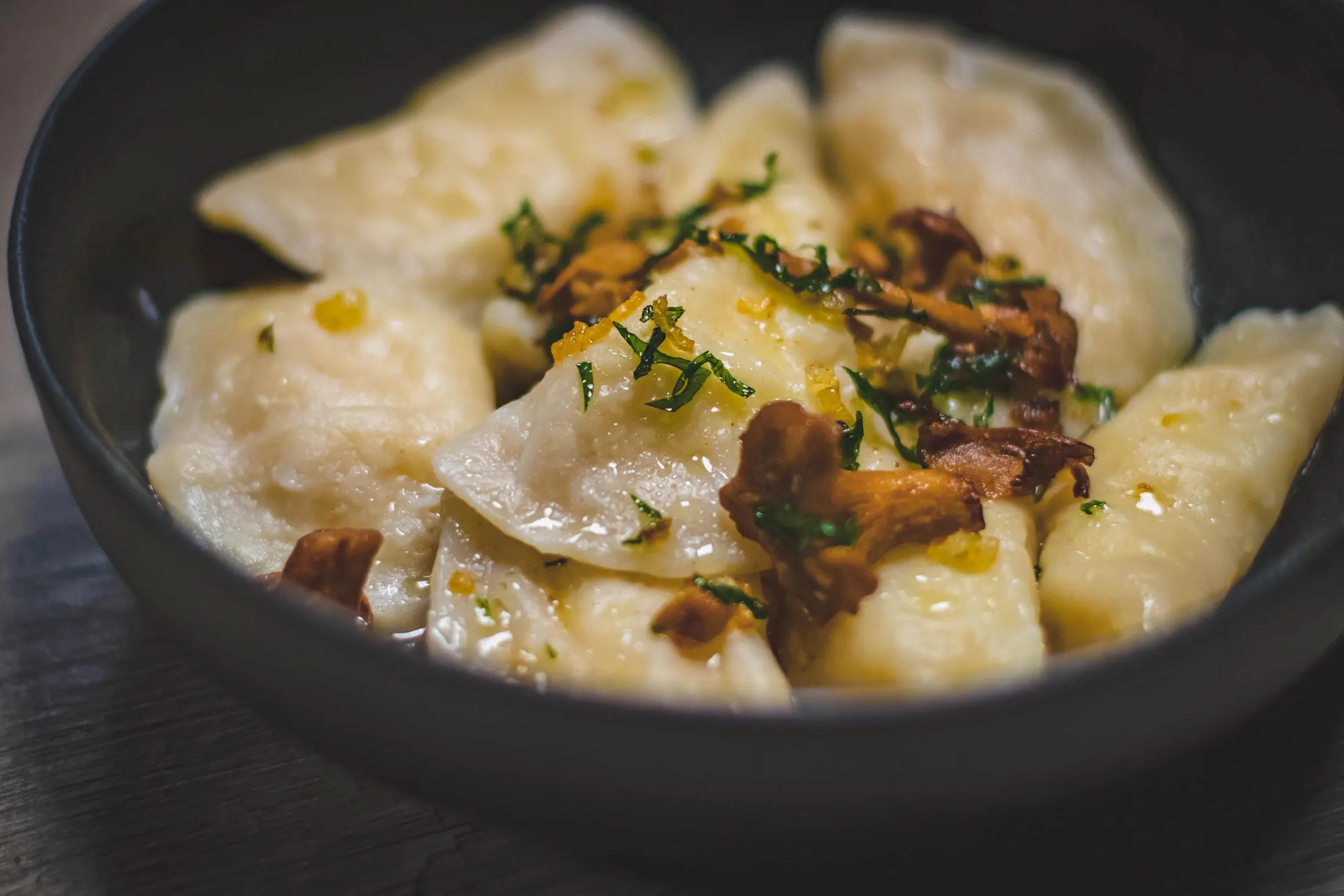 A bowl of steamed dumplings topped with herbs and mushrooms